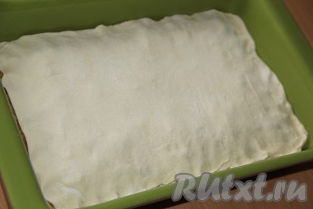 Выложить третий слой теста. Поверх выложить вторую часть кураги, присыпать оставшимся сахаром. Накрыть начинку четвёртым слоем теста. По краям можно немного скрепить края слоёного теста.