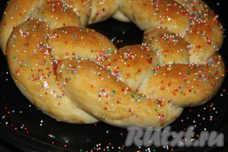 Выпекать пасхальный венок с тройной начинкой в разогретой духовке, примерно, 35 минут (до золотистого цвета) при температуре 200 градусов. Поверхность горячего венка смазать жидким мёдом и сразу присыпать цветной посыпкой.
