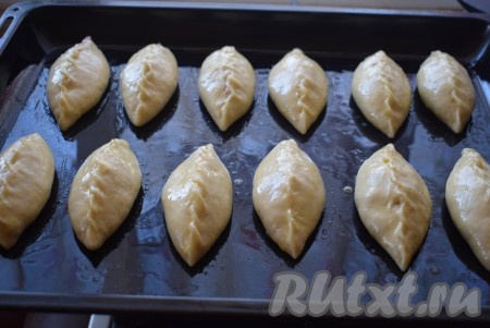 Лепим таким образом все пирожки. Кладем пирожки швом вверх на противень, смазанный растительным маслом. Так как начинка у нас пустит много сока во время выпечки, поэтому не рекомендую класть пирожки швом вниз. Пирожки с вишней с помощью кулинарной кисти смазываем смесью яйца и молока.
