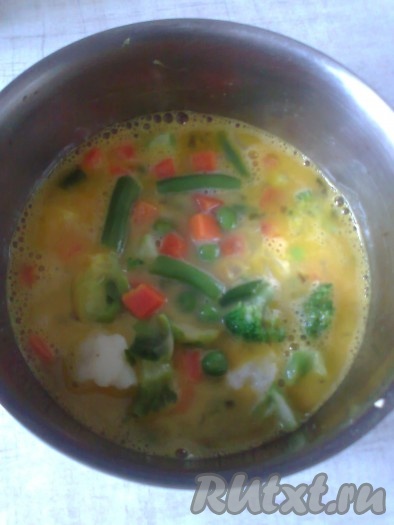 Отваренную замороженную смесь добавить к яйцам и перемешать.
