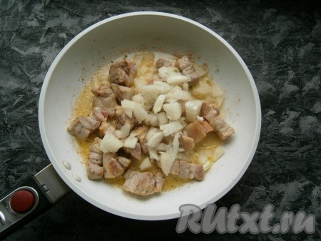 Обжарить свинину на среднем огне в течение 3-4 минут (до легкой румяности), после чего добавить очищенный и нарезанный произвольно репчатый лук.
