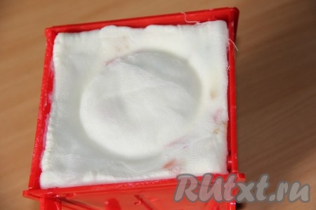 Форму для пасхи поставить в тарелку, поверх творожной массы, накрытой марлей, разместить блюдце с грузом (в качестве груза может быть, например, банка с водой). Поставить форму с грузом в холодильник на 12-15 часов. За это время в тарелку из творожной массы будет выделяться жидкость, которую нужно периодически выливать.
