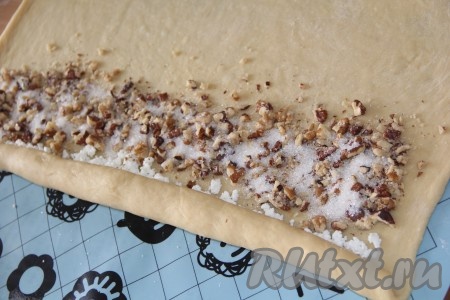 Присыпать орехи 1-2 чайными ложками сахара и продолжить заворачивать тесто в плотный рулет.
