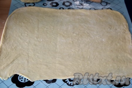 По истечении времени разделить тесто на 2 равные части (у нас в результате получится 2 рулета). Одну часть теста раскатать в прямоугольный пласт толщиной, примерно, 0,5 см.
