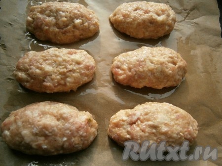 Края мясной лепешки защипнуть так, чтобы сыр оказался внутри, и сформировать продолговатую котлету. Таким же образом сформировать все мясные зразы с сыром. Противень застелить пергаментом, смазать пергамент растительным маслом, а затем выложить зразы.
