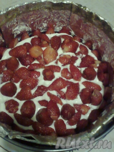 Заполните пустое пространство кремом, выложите целую клубнику, слегка вдавливая ее в крем. Промежутки заполните кусочками клубники.