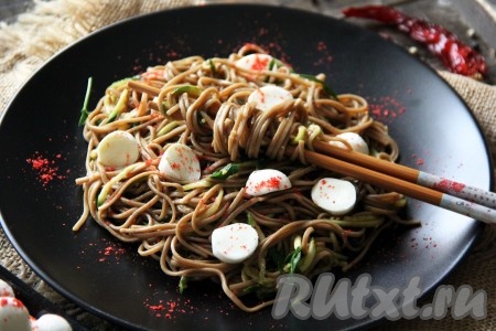 Гречневую лапшу, приготовленную с добавлением соевого соуса и кунжута, разложить по порционным тарелкам, добавить, по желанию, нарезанную моцареллу и подать к столу.