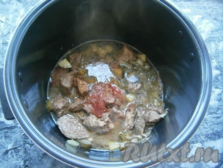 Также добавить нарезанные полукружочками соленые огурцы и обжаривать далее, иногда помешивая, до окончания программы. Затем влить горячую воду, добавить томатную пасту (или соус), всыпать соль, специи и черный молотый перец.
