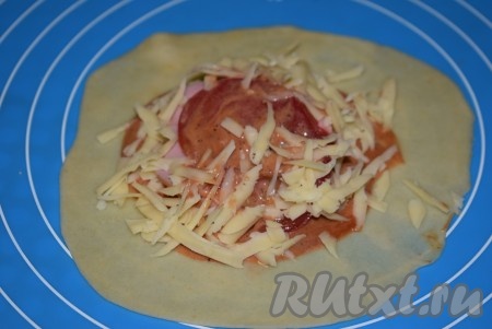 На колбасу кладем кружок помидора, смазываем соусом и сверху снова посыпаем сыром.
