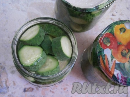 Залить огурцы кипятком, накрыть банки с огурчиками прокипяченными крышками и оставить минут на 15. По прошествии 15 минут воду из банок с огурчиками вылить в раковину и снова залить огурцы кипятком минут на 10.
