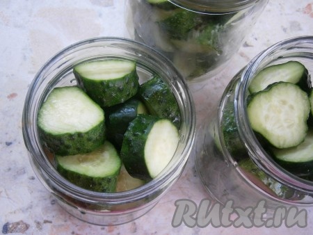 Огурцы хорошо вымыть, обрезать края с двух сторон, нарезать их в банки (периодически встряхивая) кружочками толщиной около 1 см.
