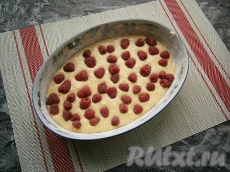 Выложить в форму половину теста, сверху разместить половину ягод малины.