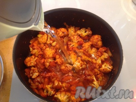 Затем в сковородку к цветной капусте с морковью добавляем стакан горячей воды.
