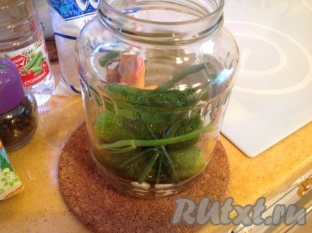 Аккуратно снимаем горячую банку, окутав полотенцем, и кладём в неё укроп, очищенный чеснок и кусочек острого перчика. Затем наполняем каждую банку огурцами с отрезанными кончиками.