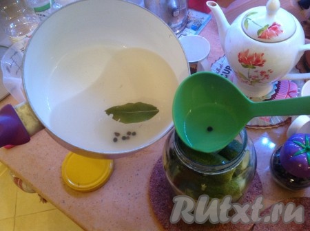 Теперь постепенно при помощи половника заливаем наши огурцы в банке маринадом, распределяя по 2 лавровых листа и 5-6 перчинок на банку.