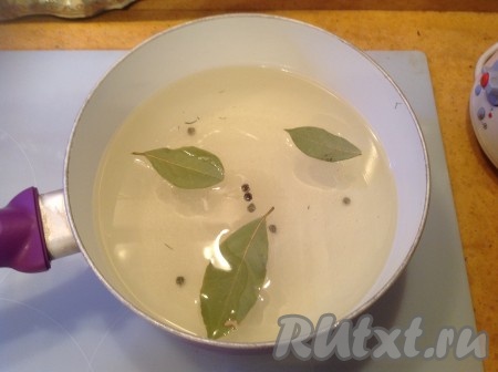 Через 30 минут сливаем воду из банок в кастрюлю и ставим на огонь. Сливаем воду из банок через крышечку с дырками (или через ситечко), чтобы не выскочил чесночок. Для приготовления маринада воду, слитую из банок, доводим до кипения, добавляем соль, сахар, перец горошком и лавровые листья, провариваем несколько минут (чтобы растворились соль и сахар).
