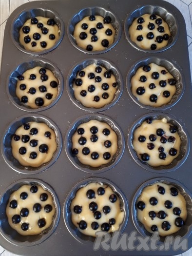 Тестом заполнить формочки для кексов на 2/3, сверху разместить ягоды черной смородины.
