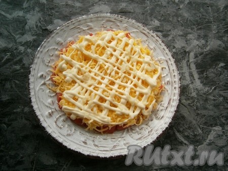 Следующим слоем выложить сыр, натёртый на средней (или мелкой) тёрке, нанести сеточку из майонеза, посыпать мелко порубленным чесноком.
