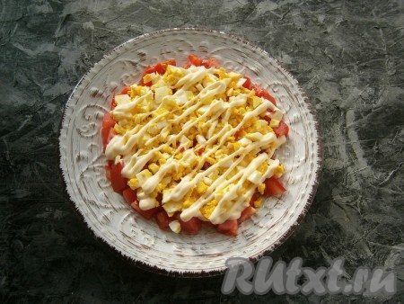 Варёные яйца очистить, порубить, равномерно выложить их на помидоры, нанести майонезную сеточку, чуть посолить.
