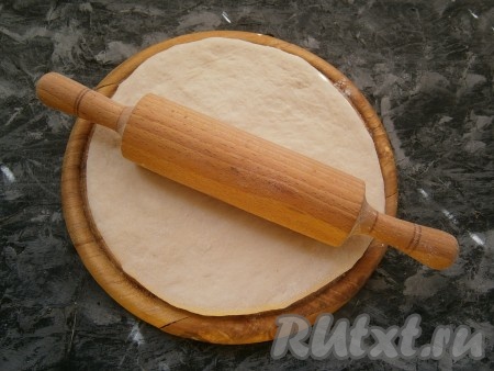 Тесто ещё раз обмять, подсыпав немного муки на стол, раскатать его в лепёшку толщиной около 1 см.
