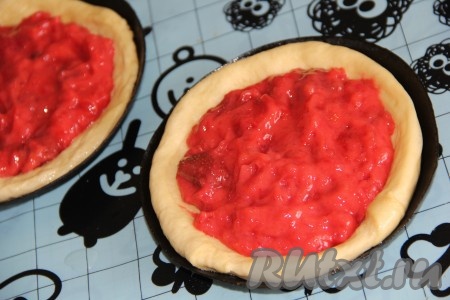 Если клубника замороженная, её нужно разморозить, а сок, образовавшийся в процессе размораживания (примерно, 150-200 мл), вылить в кастрюлю, всыпать сахар. Если готовите ватрушки со свежей клубникой, тогда налейте в кастрюлю 150-200 мл воды (можно заменить на любой фруктовый или ягодный сок), а затем всыпьте сахар. Поставить кастрюлю на средний огонь и довести ягодный сок (или воду) с сахаром до кипения, периодически помешивая. В отдельной ёмкости крахмал соединить с 200 мл холодной воды, перемешать до однородного состояния. Огонь убавить до минимума, влить тонкой струйкой крахмальную массу в кастрюлю с соком и сахаром, постоянно помешивая. Масса при варке начнёт загустевать. В кастрюлю с крахмальной массой добавить ягоды клубники, перемешать, довести массу до кипения и снять с огня. Остудить начинку (я начинку сделала накануне приготовления ватрушек). Выложить на середину каждой ватрушки начинку. У меня получилось 7 ватрушек диаметром 10-11 см.
