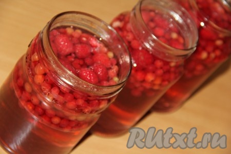 Горячим сиропом полностью залить банки с красной смородиной и малиной, накрыть заранее прокипячёнными крышками.
