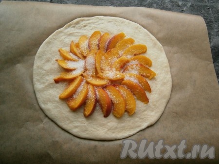 Персики вымыть, обсушить, удалить косточки. По центру теста, не доходя до краёв 7-8 см, выложить нарезанные дольками персики, посыпать их 2 столовыми ложками сахара.
