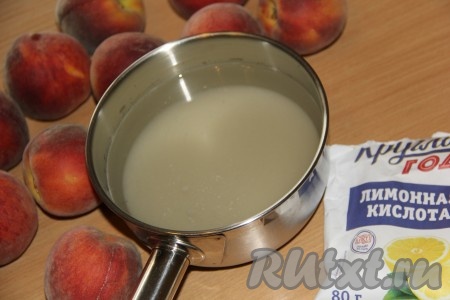 Персики хорошо вымыть. В кастрюлю налить воду, всыпать лимонную кислоту и сахар, поставить на огонь.
