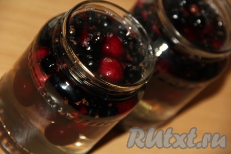 Банки с чёрной смородиной и черешней заполнить горячим сиропом до самого верха, прикрыть крышками.
