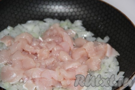 Нарезать куриное филе на маленькие кусочки и выложить в сковороду к обжаренному луку.
