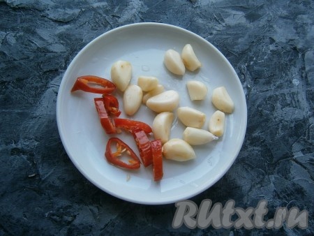 Чеснок очистить. Горький перец, не очищая от семян, нарезать колечками.

