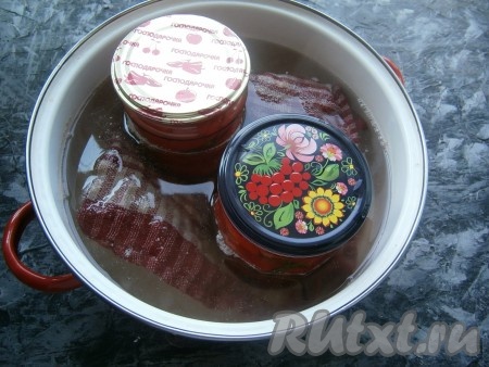 Накрыть банки крышками и поместить в кастрюлю с кипящей водой, на дно которой положить сложенную в 2-3 раза тряпочку (или полотенце). Стерилизовать банки с перцем на среднем огне в течение минут 15 с момента закипания воды.
