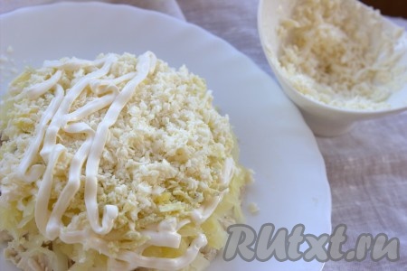 Натереть на мелкой тёрке плавленный сыр (чтобы сыр было легче натирать, его заранее можно поместить минут на 10-15 в морозилку) и выложить поверх желтков, сделать майонезную сеточку.