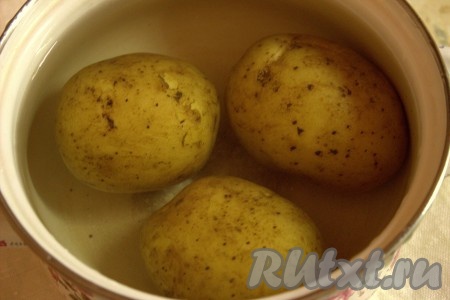 Тщательно вымытый картофель, не очищая от кожуры, сложить в кастрюлю подходящего размера, залить водой и поставить вариться. Когда вода закипит, уменьшить огонь, накрыть кастрюлю крышкой и варить картошку до готовности (25-30 минут, картошка не должна развариться). Чтобы убедиться, что картошка готова, нужно проткнуть её вилкой (или ножом), если клубень легко прокалывается, значит картофель готов. С готовой картошки слить воду, дать остыть.