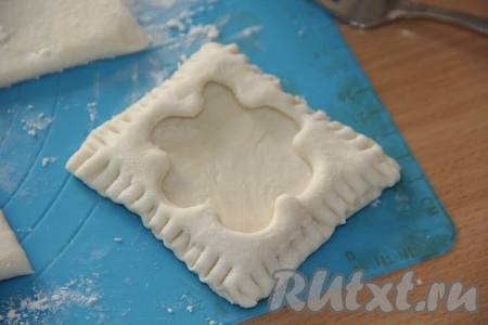 Сформировать слойки: на квадрат теста выложить квадратик с вырезанным цветочком и скрепить края вилкой (как на фото).
