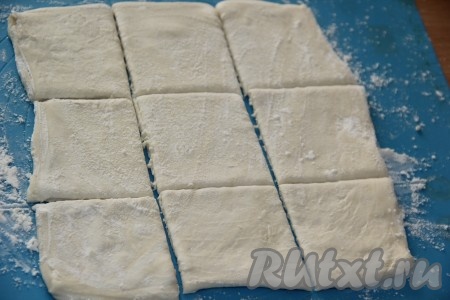 У меня покупное слоёное тесто было в виде 2 пластов. На столе, присыпанном мукой, слегка раскатать каждый пласт теста и нарезать на квадратики (я разрезала каждый пласт теста на 9 квадратов).
