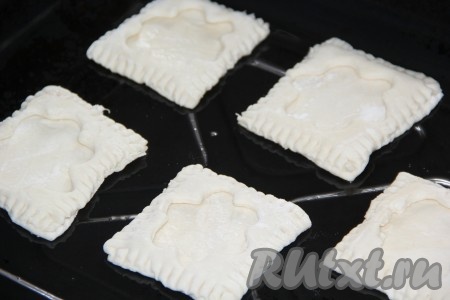Выложить слойки на противень, смазанный растительным маслом.
