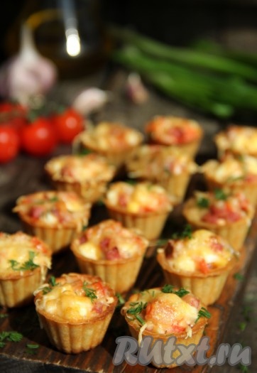 Запекать тарталетки с начинкой в разогретой духовке минут 5 при температуре 180 градусов. Вкусные, сытные тарталетки с колбасой и сыром подать к столу в горячем виде. Закуска готовится за считанные минуты, а получается такой аппетитной, что непременно будет съедена одной из первых!
