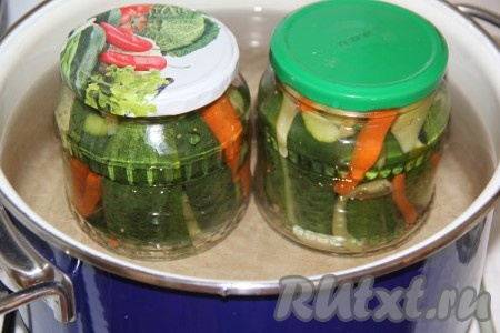 На дно достаточно большой кастрюли поместить тряпочку, сложенную в несколько раз (тряпочка нужна, чтобы банки не лопнули во время стерилизации), влить тёплую воду. Поместить в эту кастрюлю банки с огурцами, перцем и морковью (желательно, чтобы вода в кастрюле доходила до "плечиков" баночек) поставить на средний огонь. После того как вода в кастрюле закипит, стерилизовать банки 12 минут.
