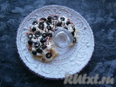 Слой колбасы смазать майонезом, далее выложить кружочки оливок.
