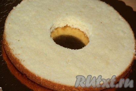На подложку выложить одну часть белого бисквита и сделать с помощью стакана в середине отверстие. Пропитать этот бисквит любой пропиткой. Я пропитала медовым сиропом. Для приготовления медового сиропа я соединила 500 мл воды и 100 мл мёда - этого количества мне хватило для пропитки всего торта.
