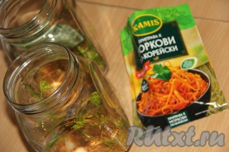 На дно каждой простерилизованной банки выложить 3 горошины чёрного перца, щепотку семян горчицы, 1 горошинку душистого перца, 2 зубчика чеснока, веточку укропа и 1/2 чайной ложки приправы для моркови по-корейски.
