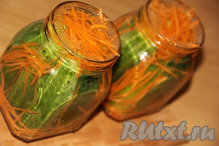 Залить банки с огурцами и морковью горячим маринадом до самого верха.
