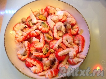 Чесночок обжарился, удаляем его и выкладываем на сковородку морепродукты.