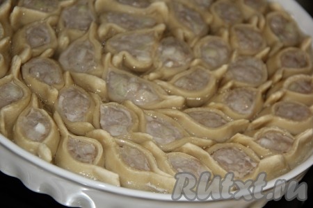 Затем достать форму и налить горячую воду до бортиков формы (вода должна быть чуть выше середины мантов, как на фото). Поставить форму с мантами в духовку и готовить до полного испарения воды (у меня на это ушло 30 минут).&nbsp;
