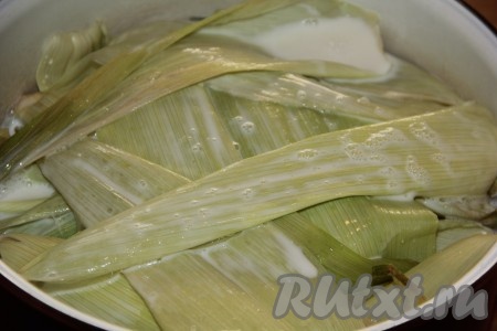 Соединить воду с молоком и влить в кастрюлю (жидкость должна почти полностью покрывать листья кукурузы). Поставить кастрюлю на огонь и довести молоко с водой до кипения, затем убавить огонь до минимума и варить кукурузу под крышкой 20 минут.
