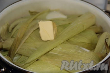 Затем положить кусочек сливочного масла на листочки и варить кукуруза в молоке ещё 10 минут. За это время зёрна кукурузы станут мягкими.
