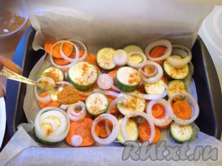 Лук, разделив на колечки, и чеснок выложить поверх моркови и кабачков. Посолить овощи, поперчить и посыпать приправой.