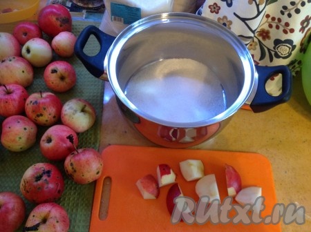 На дно кастрюли насыпать немного сахара и выкладывать слоями нарезанные яблоки, предварительно вырезая все естественные повреждения и тёмные точки.
