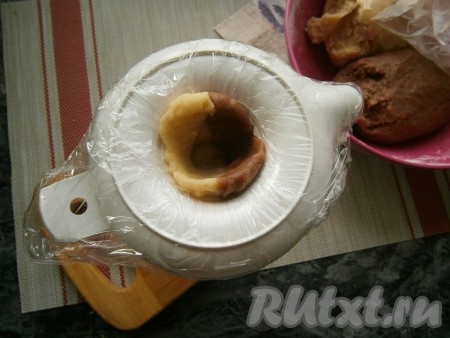 Нижнюю часть соковыжималки (с выемкой) застелить пищевой плёнкой. Для удобства можно поставить соковыжималку в стакан. Отщипнуть по небольшому кусочку светлого и тёмного теста, сложить вместе и вдавить его в выемку соковыжималки, делая пальцем отверстие (как на фото).
